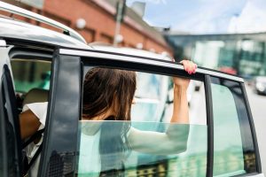 car window problems, woman stepping out of car with window stuck