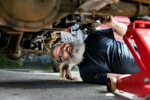 regular car maintenance, mechanic inspecting underside of car