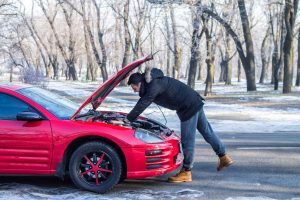 prepare your car for winter, man examining car engine under open bonnet