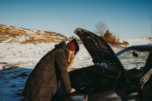 Winter car problems, woman looking under the bonnet of her car.