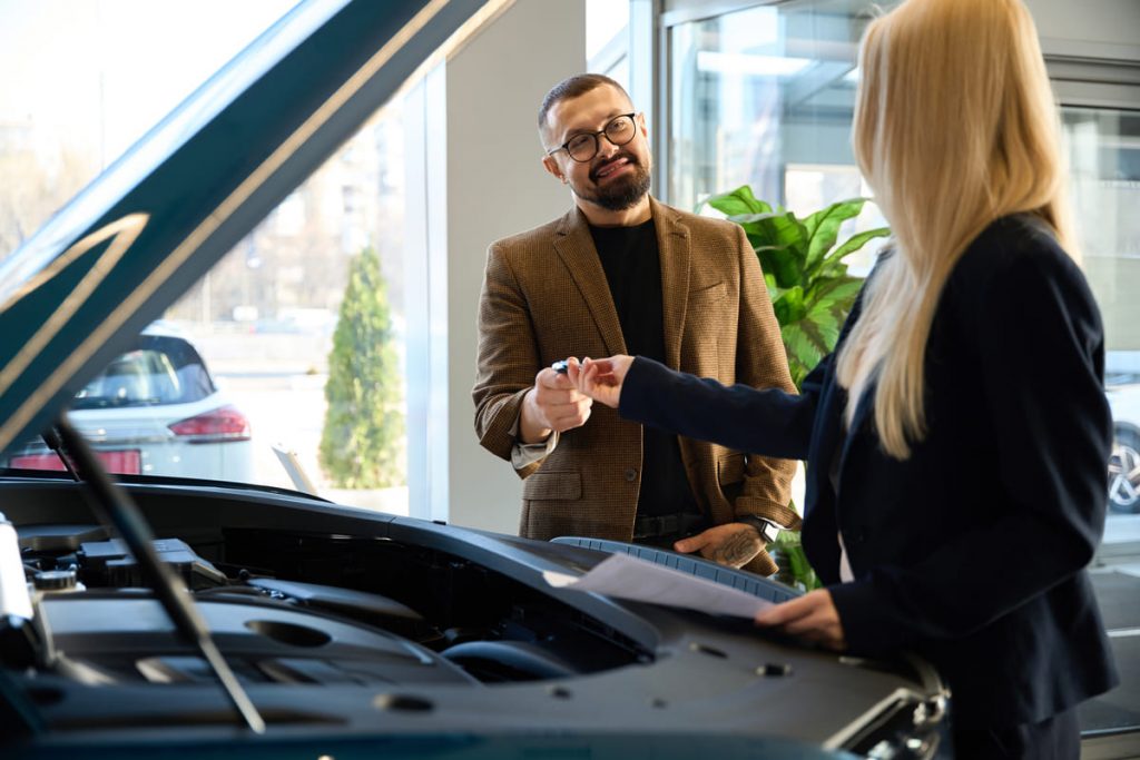 A dealer guiding a client on what to look for when buying a used car.