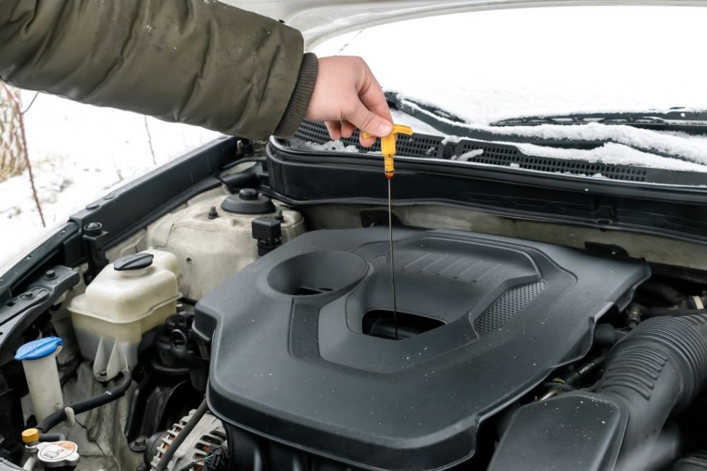 engine oil grades meaning, a car mechanic checking the engine oil level of a vehicle