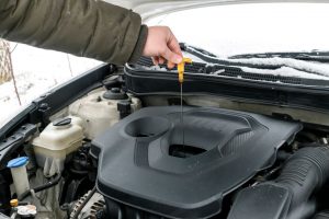 engine oil grades meaning, a car mechanic checking the engine oil level of a vehicle