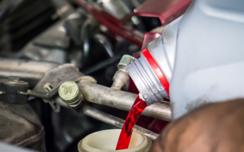 echanic pouring transmission fluid into a vehicle system