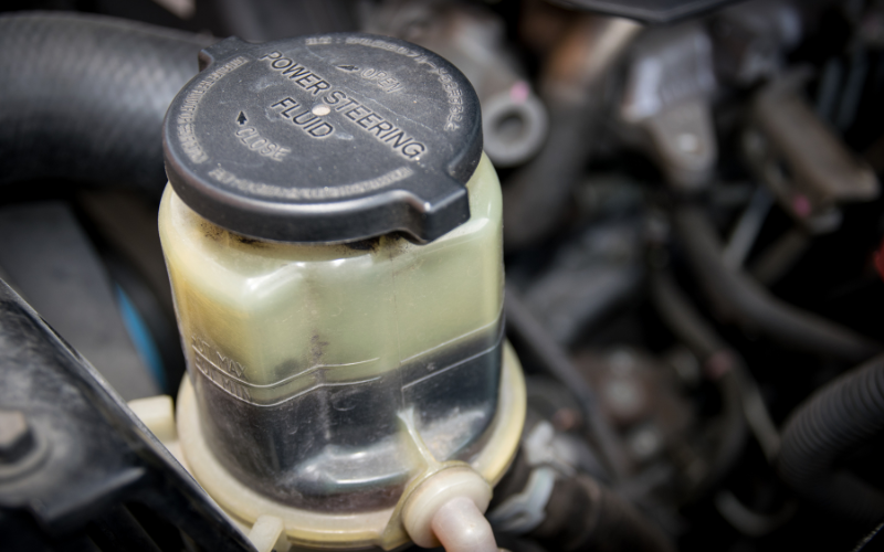 Power steering fluid reservoir inside a car engine bay