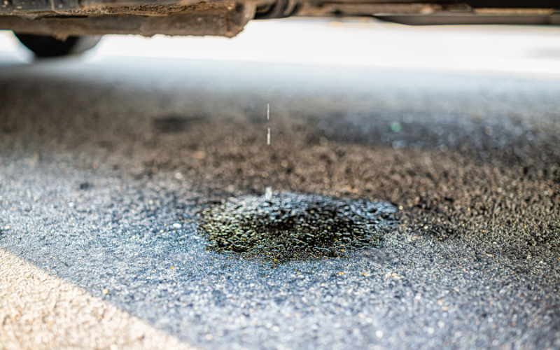 Fluid leaking underneath a parked car, which could indicate a fuel system problem or leak.