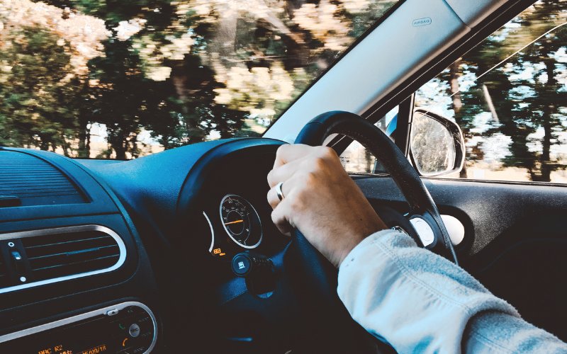 Driver holding the steering wheel while driving on the road