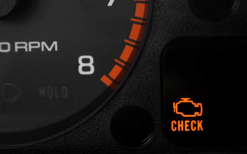Check engine warning light illuminated on a vehicle dashboard, which may indicate an engine or fuel system fault.