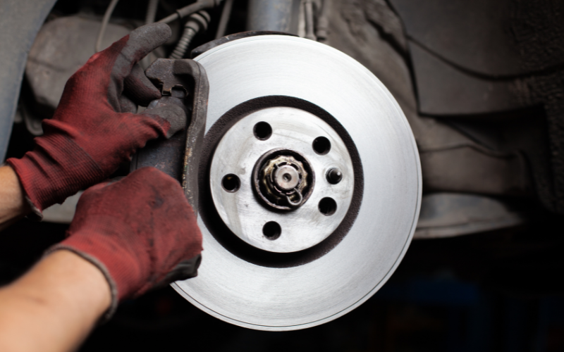 Mechanic replacing worn brake pads during routine vehicle maintenance