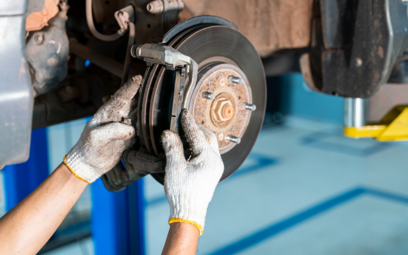 Mechanic inspecting a car's brake pads and brake disc