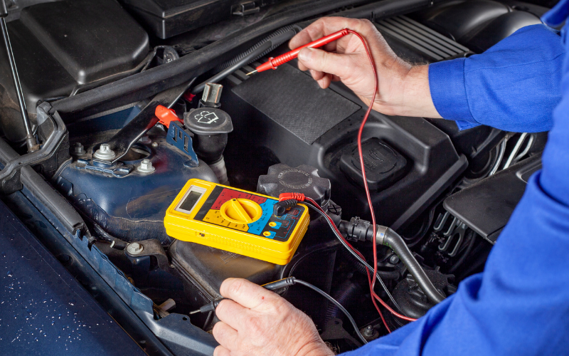 Mechanic using a digital multimeter to test a car's electrical system